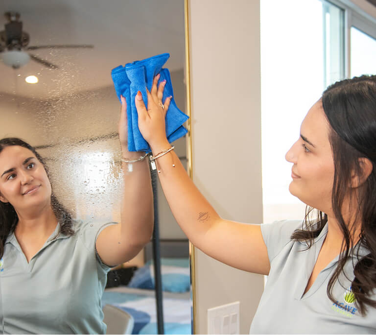 Cleaning tech wiping mirror with a smile
